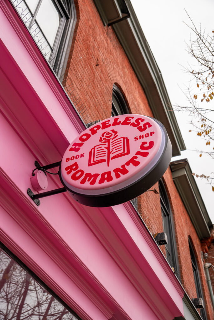 Pink storefront sign for Hopeless Romantic Books on Queen Street West in Toronto.